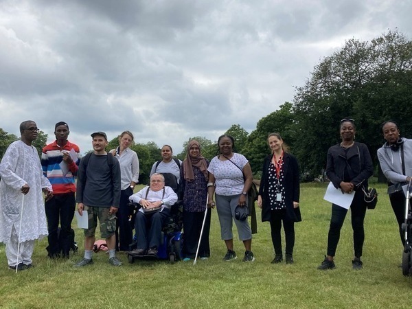 A group of diverse people in a Lambeth park.  Visible are walking aids, including a crutch, a white stick, and wheelchair.  